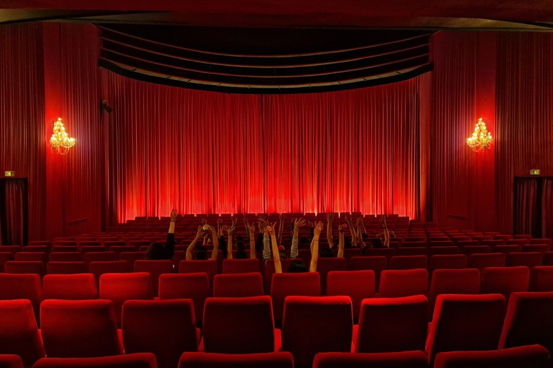 Klasse 8b im Kino, von hinten, Haende in die Luft gestreckt